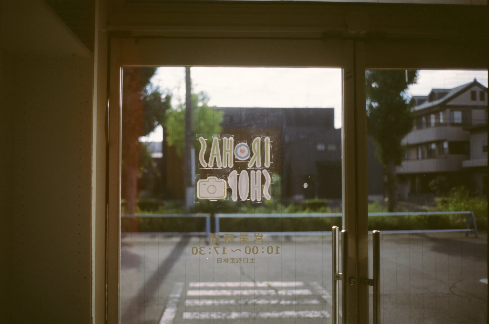 The IROHAS SHOP sign on the glass door of Irohas Camera in Maebashi, seen from inside